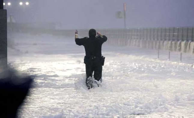 Un agent de la Policia municipal de Sant Sebastià envoltat per l'onatge al Paseo Nuevo, que continua tancat pel consistori donostiarra en previsió de les fortes ràfegues de vent al litoral i onades de fins a 7 metres durant la plenamar.