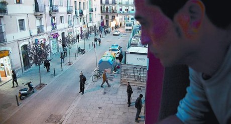 Un ve� de l'Illa Robador mira per la finestra del seu pis cap al carrer que tants maldecaps li provoca, dijous passat a la tarda.